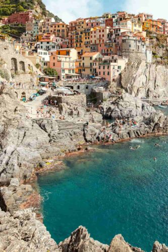 Colorful houses perched on rocky cliffs in Manarola, one of the five picturesque villages of Italy's Cinque Terre, overlooking the sea. (Photographer: Laura Adai)