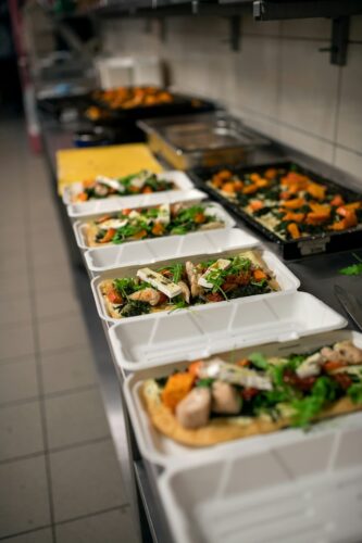 Vegetable-based meals assembled in a long line of to-go boxes.
