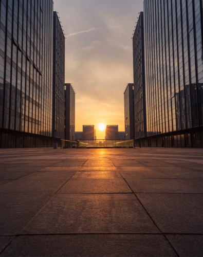 City with buildings on both sides and the sun setting in the middle