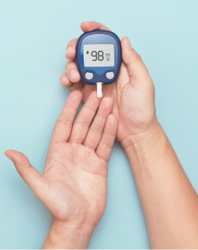 Person testing blood sugar by holding monitor which says 28