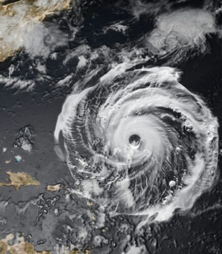 Satellite image of a powerful hurricane with a clearly defined eye swirling over the Atlantic Ocean, approaching landmasses in the Caribbean.