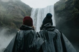Two people standing in front of a waterfall. Photograph by A.C.