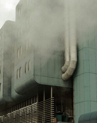 A gray building emits smoke.