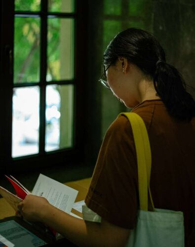 A woman standing in front of a window holding a piece of paper