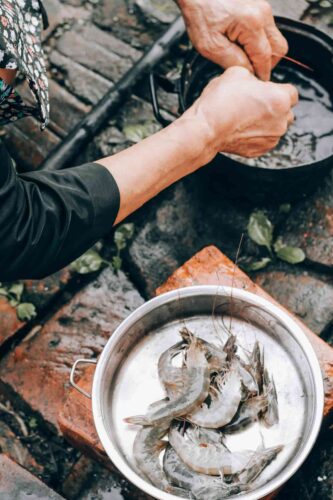 Person holding stainless steel bowl with shrimp. Photograph by Nguyen Dang Hoang Nhu.