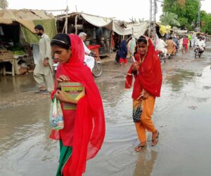 Women passing through a road overflowing with water in Naundero, Pakistan. Photo by Jamal Dawoodpoto.
